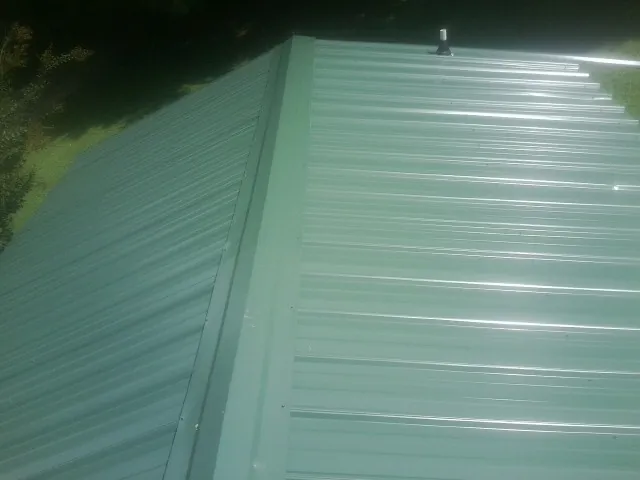 New green metal panels meeting at the ridge of a roof — Flat Roof Repair work by our crew in Maybrook