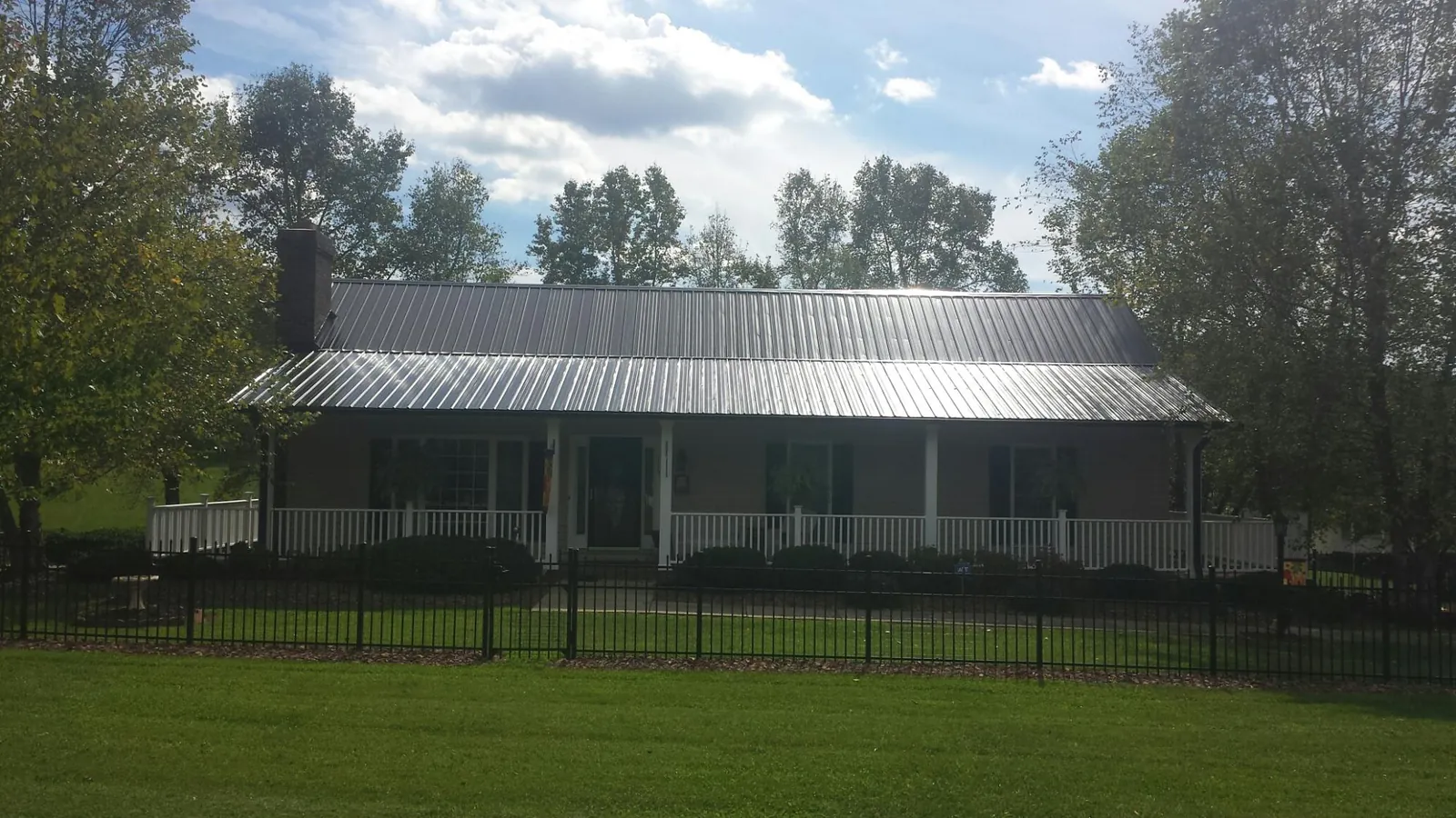 Gray metal roof on a brick ranch with a full width front porch — Gutter Guard Installation work by our crew in Maybrook