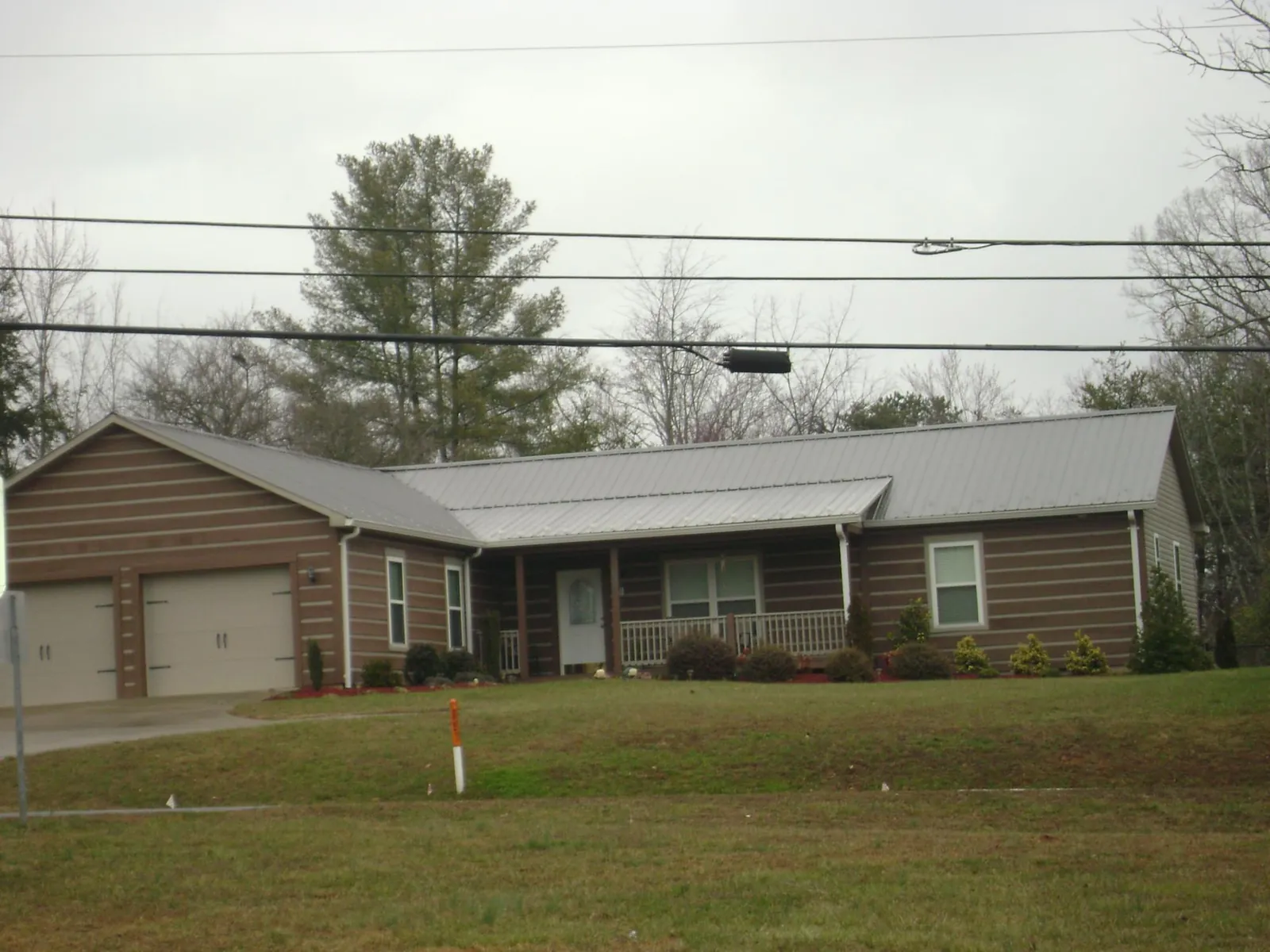 Gray metal roof on a log sided ranch home with a front porch in Maybrook