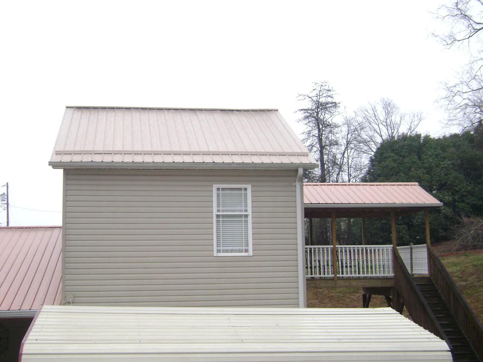 Tan metal roofs on a two story addition and attached porch, from a Roof Replacement job in Maybrook