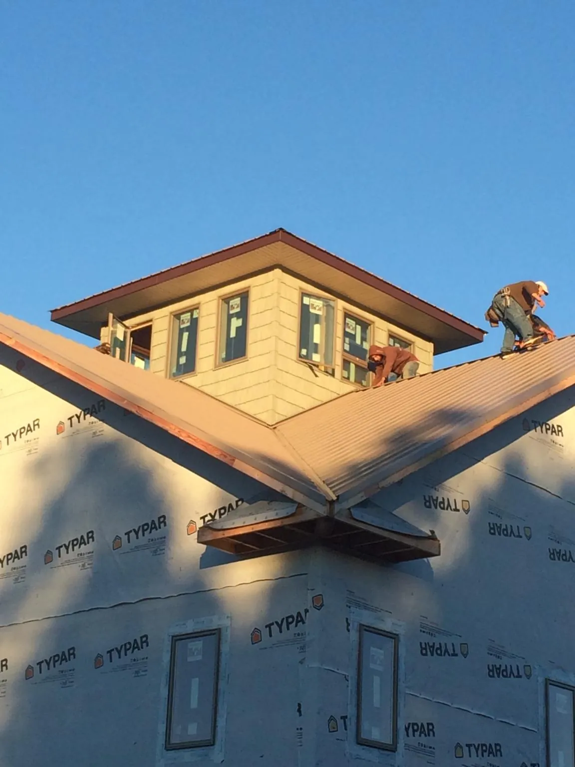 Roofers working around a rooftop cupola on a new metal roof at sunset — Roof Waterproofing in Maybrook by Roofing Brothers